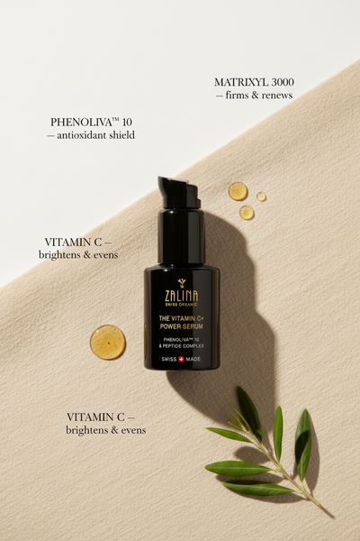 Vitamin C+ Power Serum ingredient flatlay with Phenoliva olive branch and serum droplets on beige