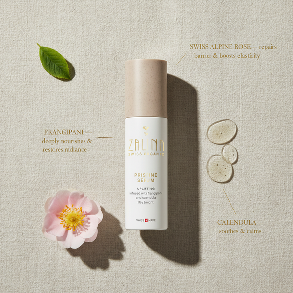 Pristine Serum ingredient flatlay with Alpine Rose and frangipani on beige stone